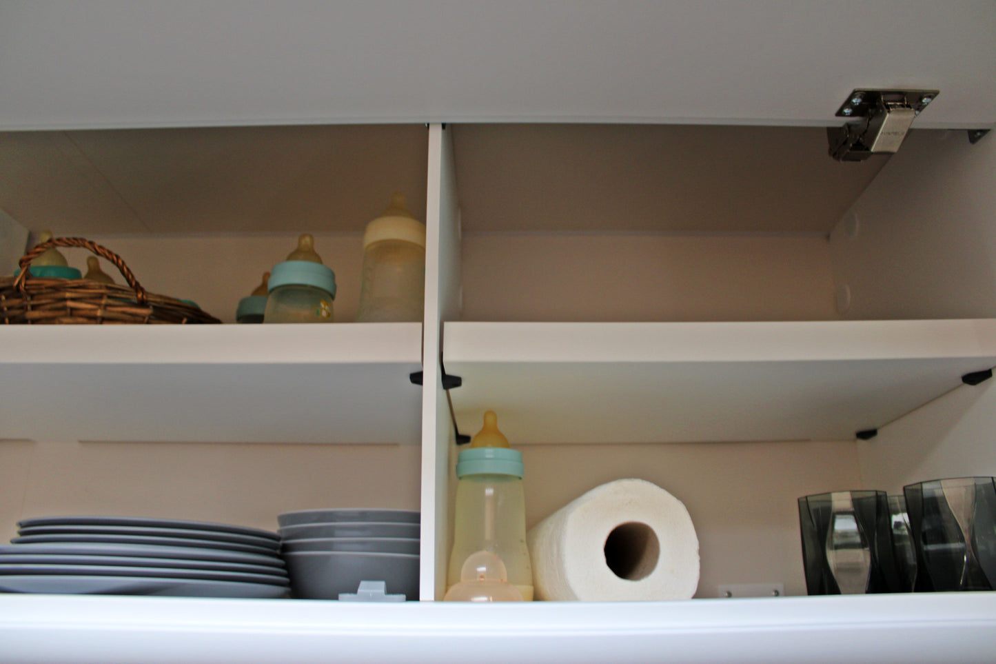 Ein kompaktes Wohnwagmobil-Interieur mit einem eingebauten Schrank an einer Wand, ordentlich organisiert mit verschiedenen Gegenständen im Inneren.